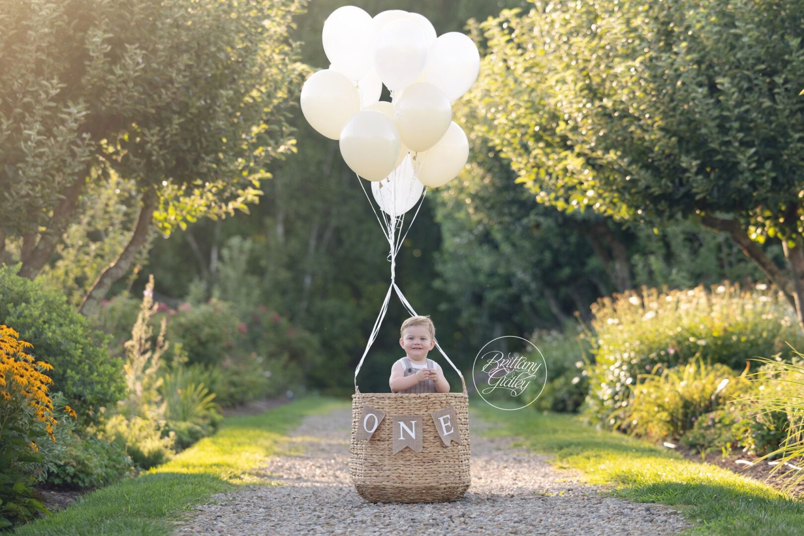 One year old boy in a balloon basket with ONE letters on a garden path at Stan Hywet Hall and Gardens