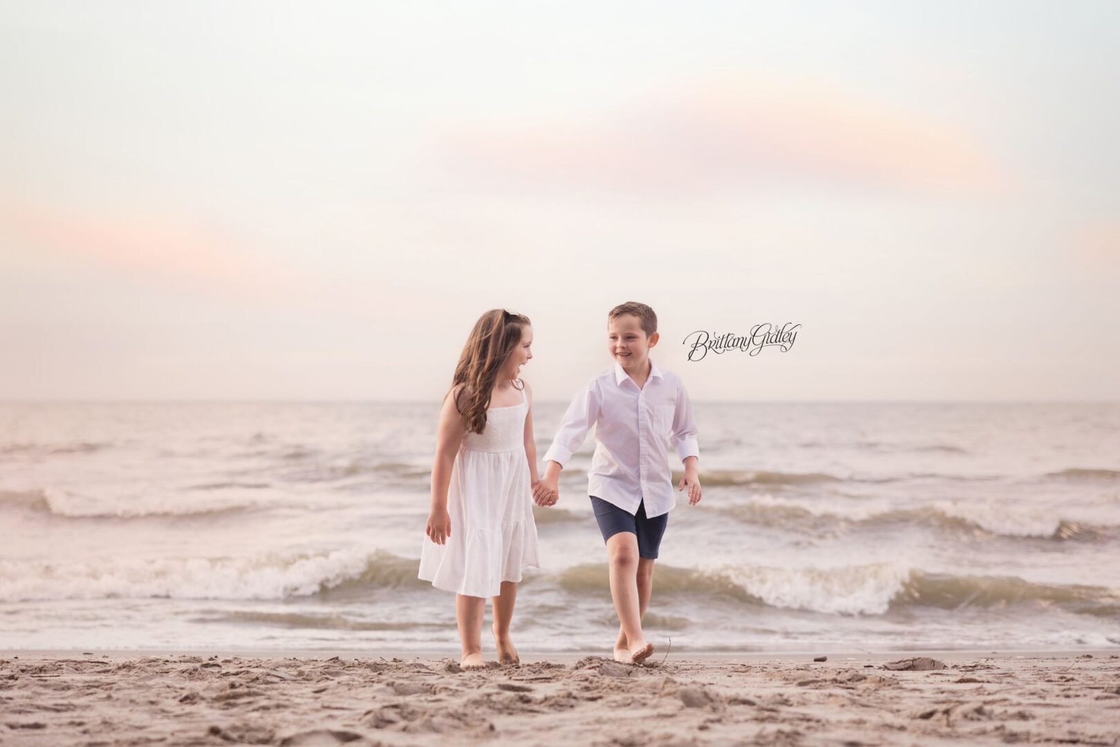 Brother and sister holding hands in the Lake Erie waves at sunset in Bay Village, Ohio