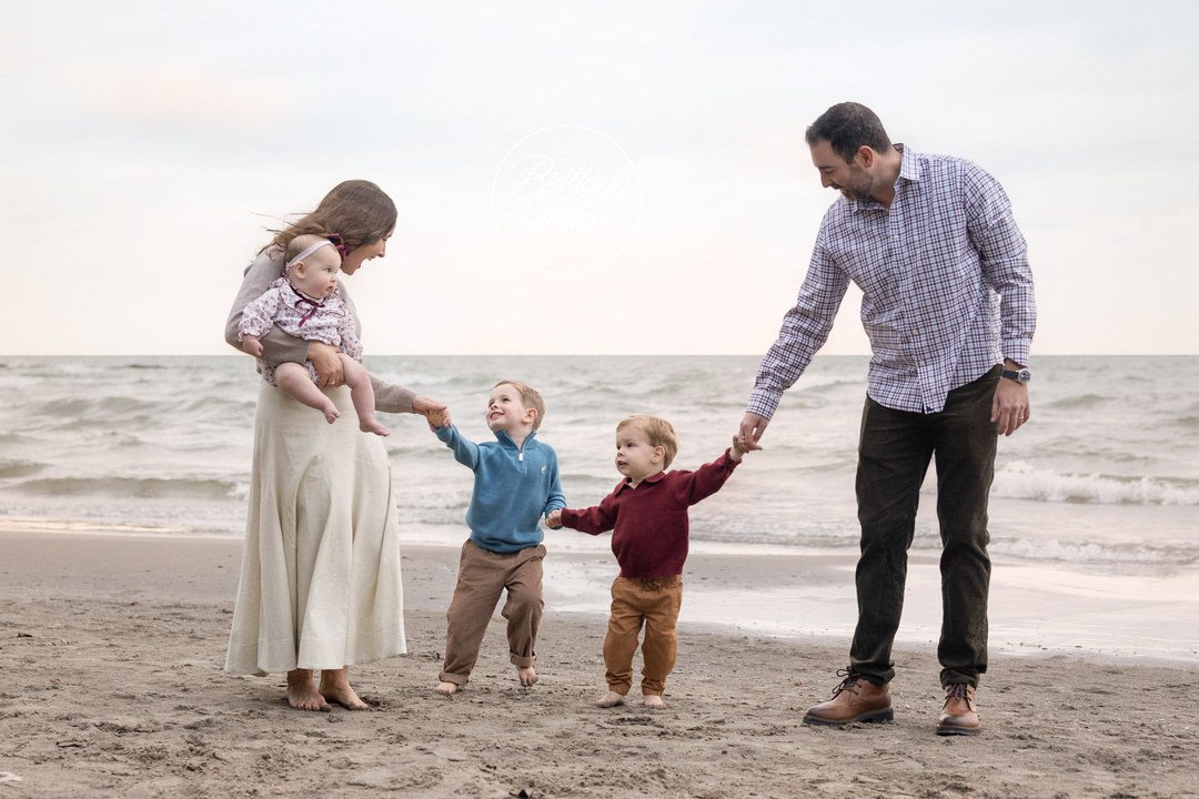 Family holding hands and walking along the Lake Erie shoreline at Huntington Beach