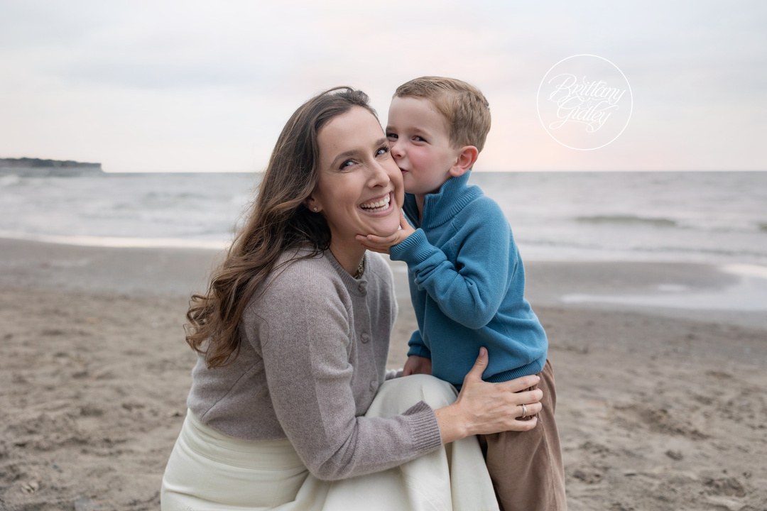 Little boy kissing his mom's cheek during a fall family session on the beach