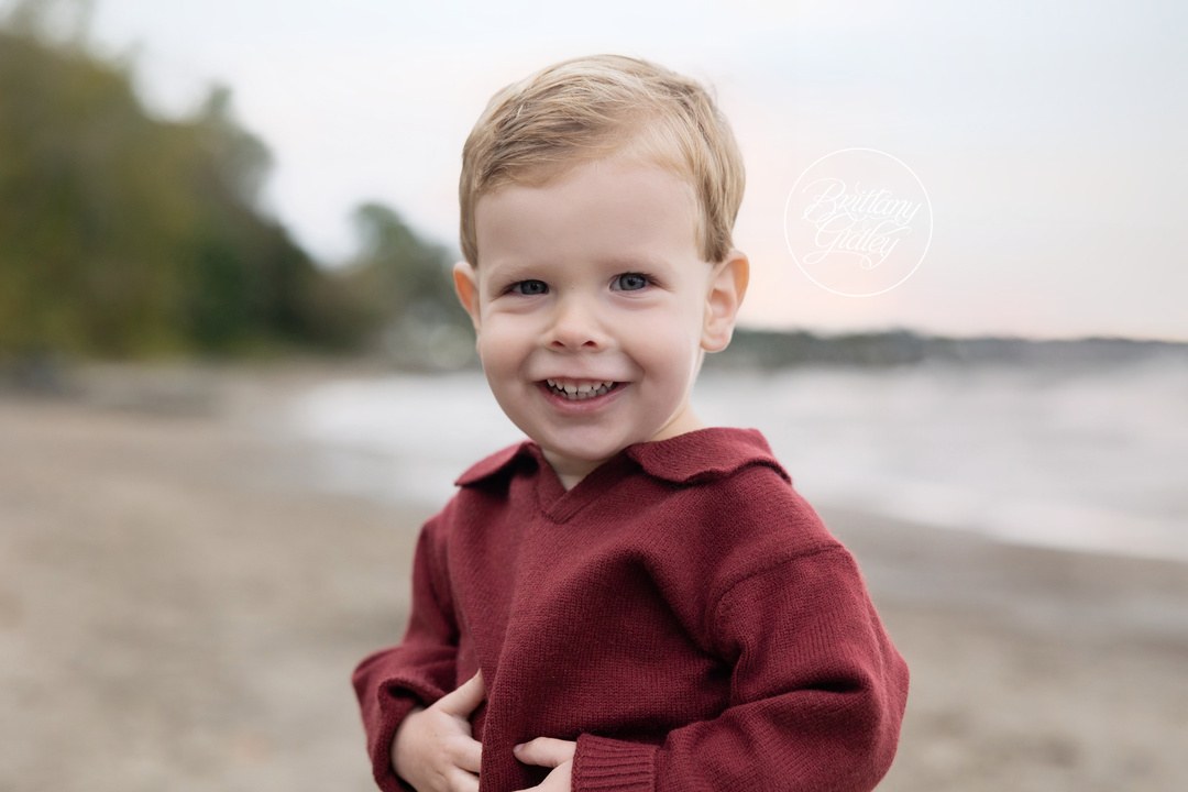 Happy toddler boy in a red sweater on the beach in Bay Village, Ohio
