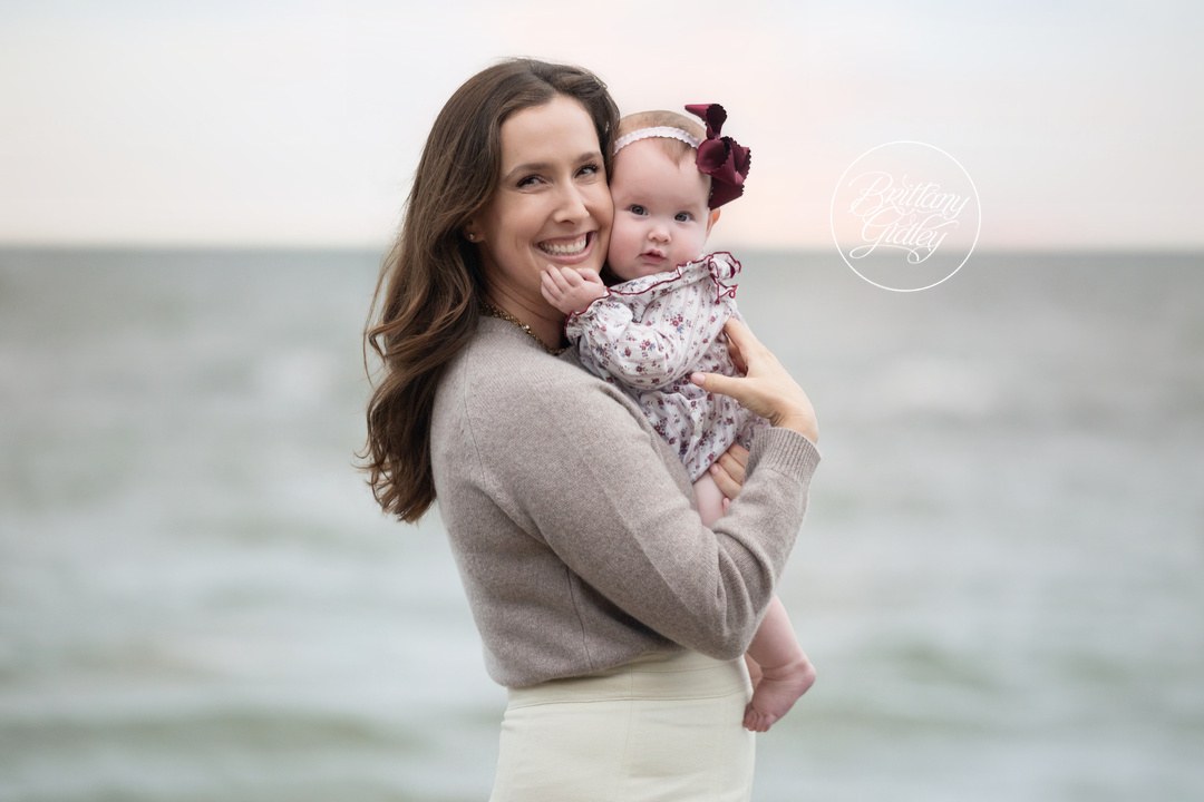 Mom snuggling her baby daughter in front of Lake Erie in Bay Village, Ohio