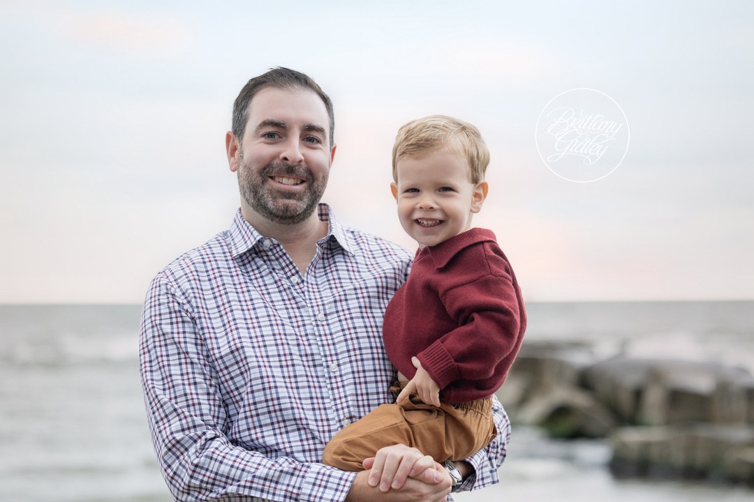Dad holding his smiling toddler son on Huntington Beach