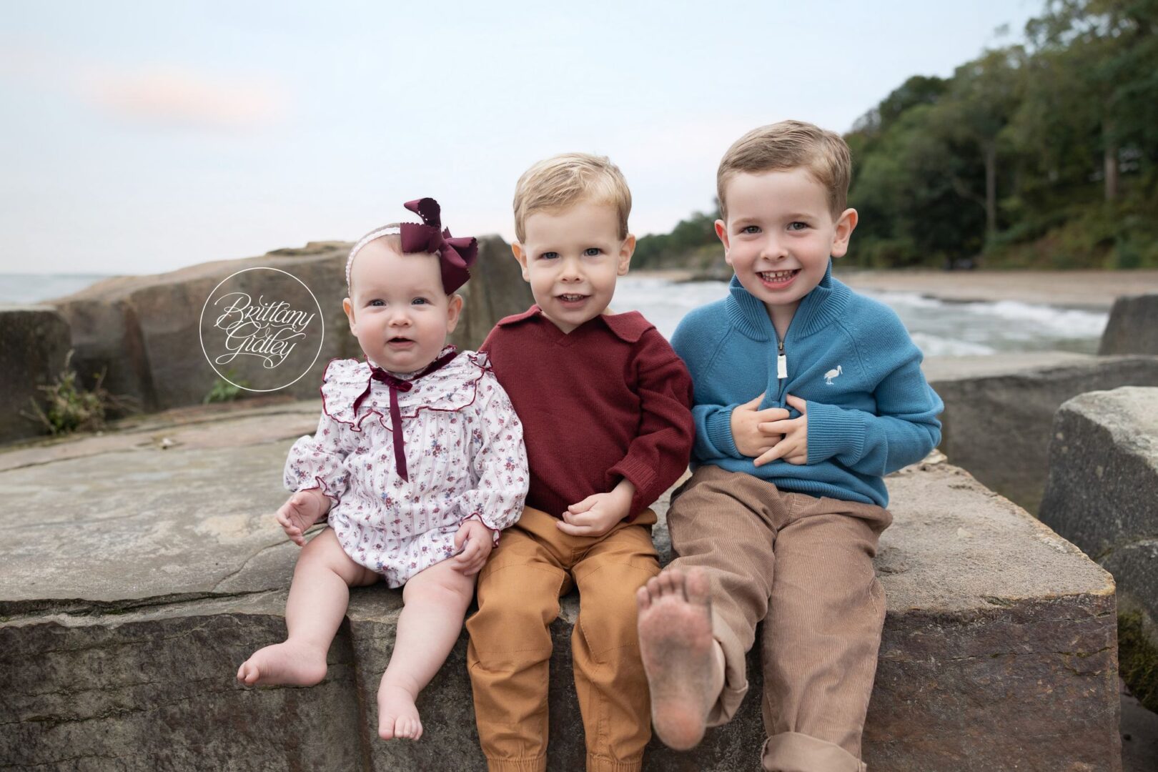Three siblings sitting together on the rocks at Huntington Beach in Bay Village, Ohio