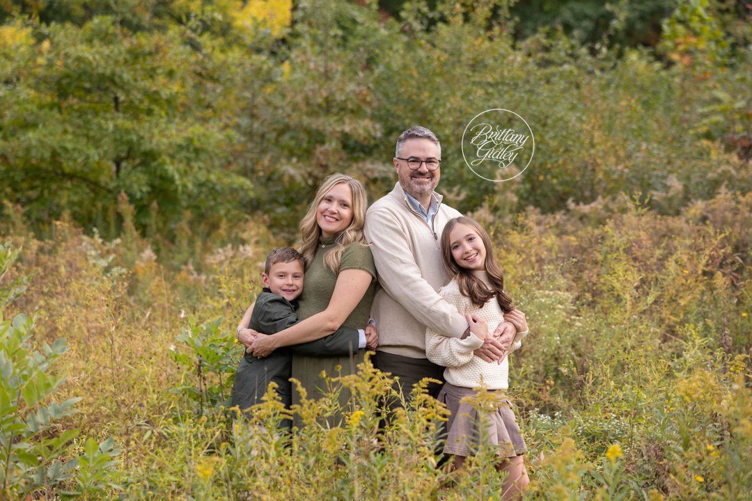 Family hugging in tall golden goldenrod during a fall birthday photo shoot