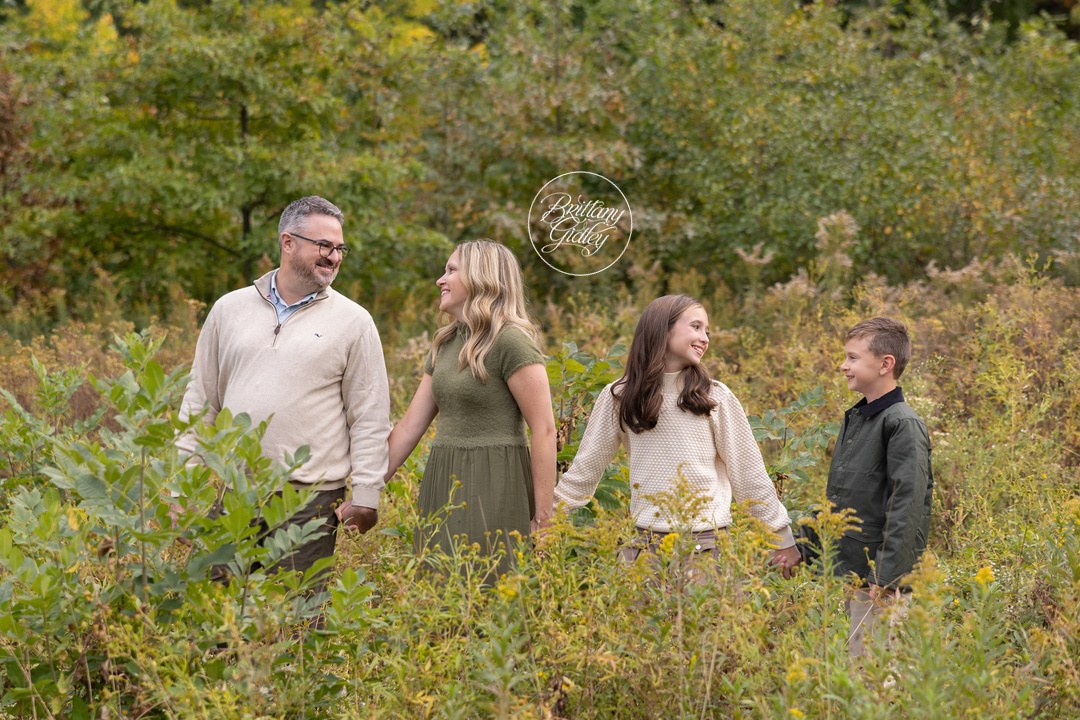 Mom, Dad, daughter and son holding hands in an autumn field near Huntington Beach