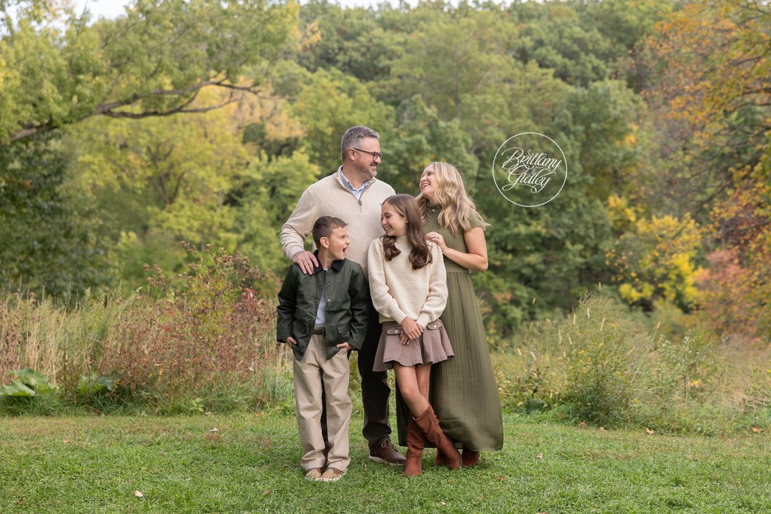 Family of four smiling and laughing together on the grass at Bay Field