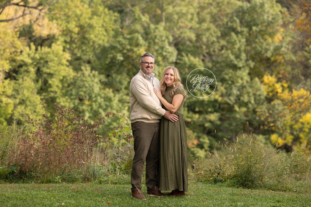 Mom and Dad embracing in a green meadow during their family session