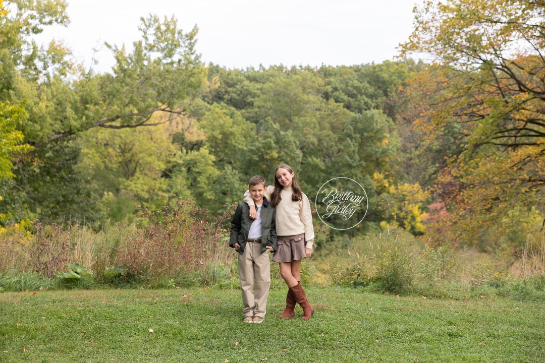Sister and brother standing together in a wide fall meadow at Bay Field