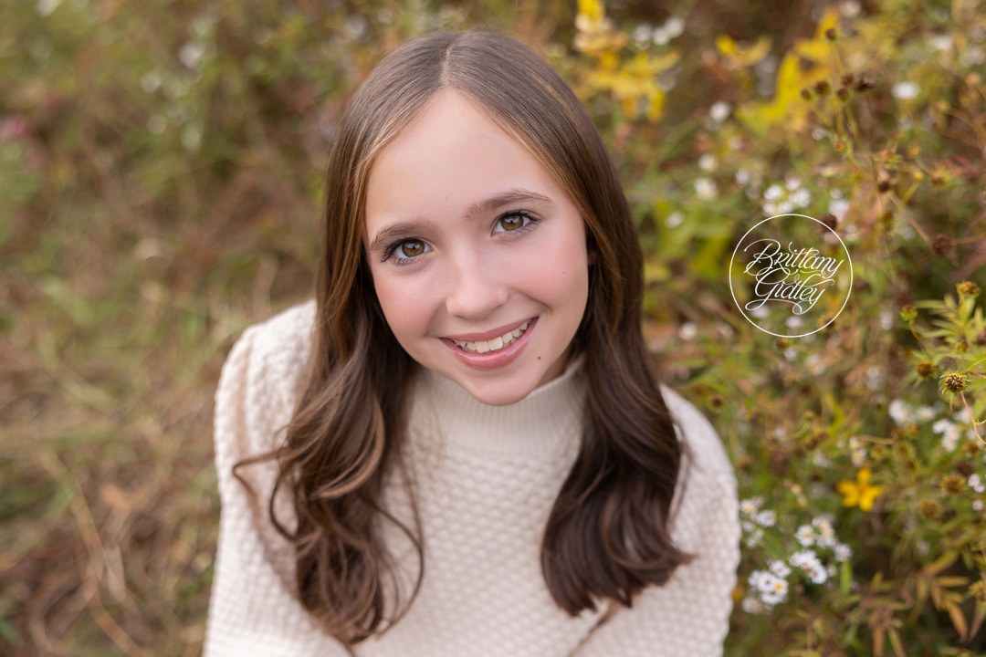 Teenage girl in a cream sweater smiling among fall wildflowers in Bay Village, Ohio