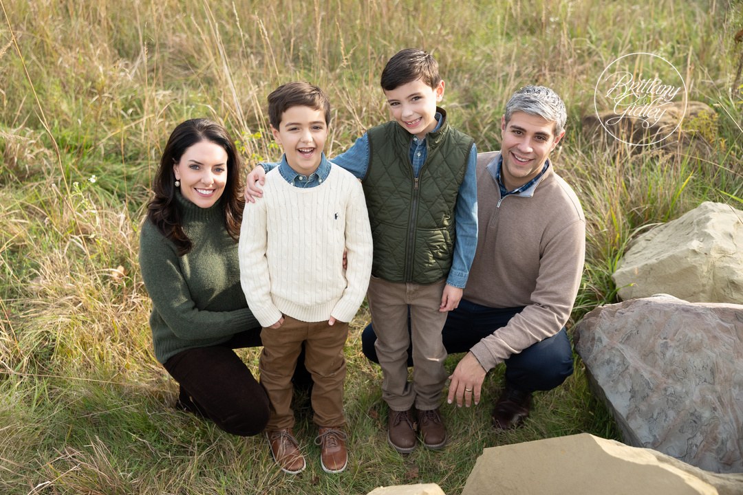 Family of four smiling together in tall autumn grass at Brecksville Reservation, Ohio
