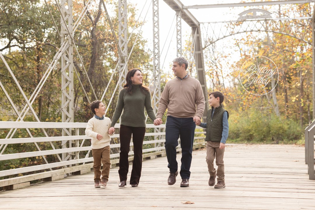 Family holding hands walking across the white bridge at Brecksville Reservation