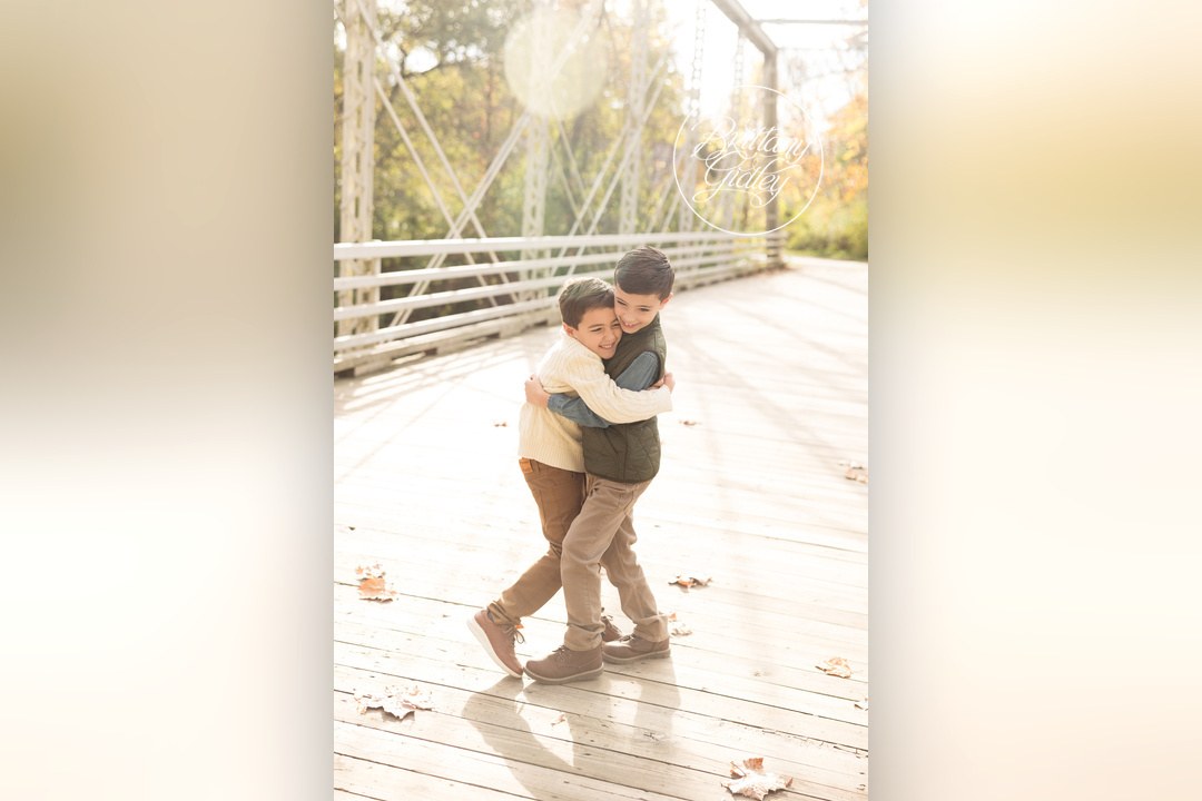 Big brother hugging his little brother on a sunny bridge in Brecksville, Ohio