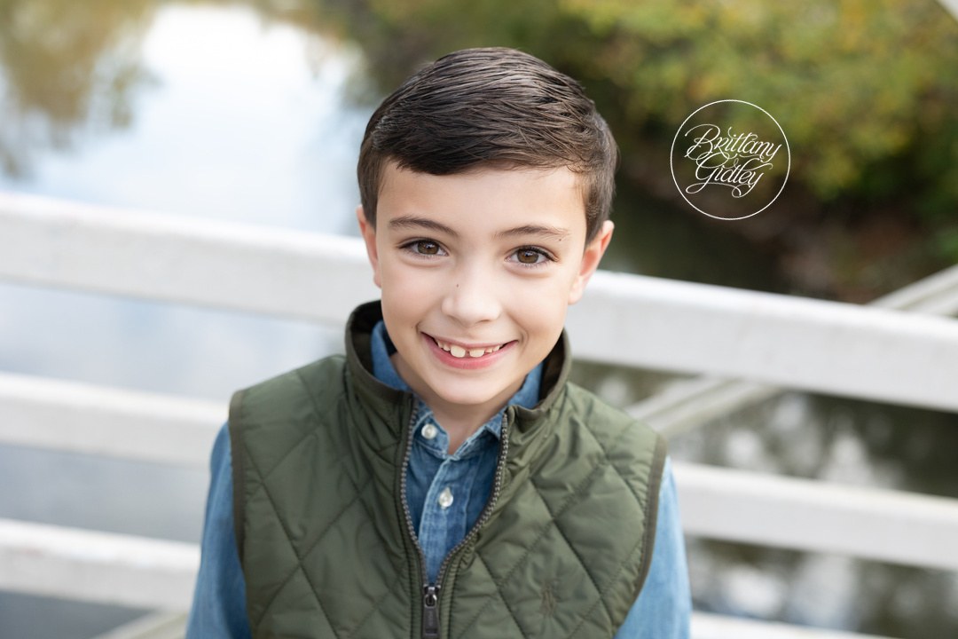 Smiling older boy in a green vest by the bridge railing at Brecksville Reservation