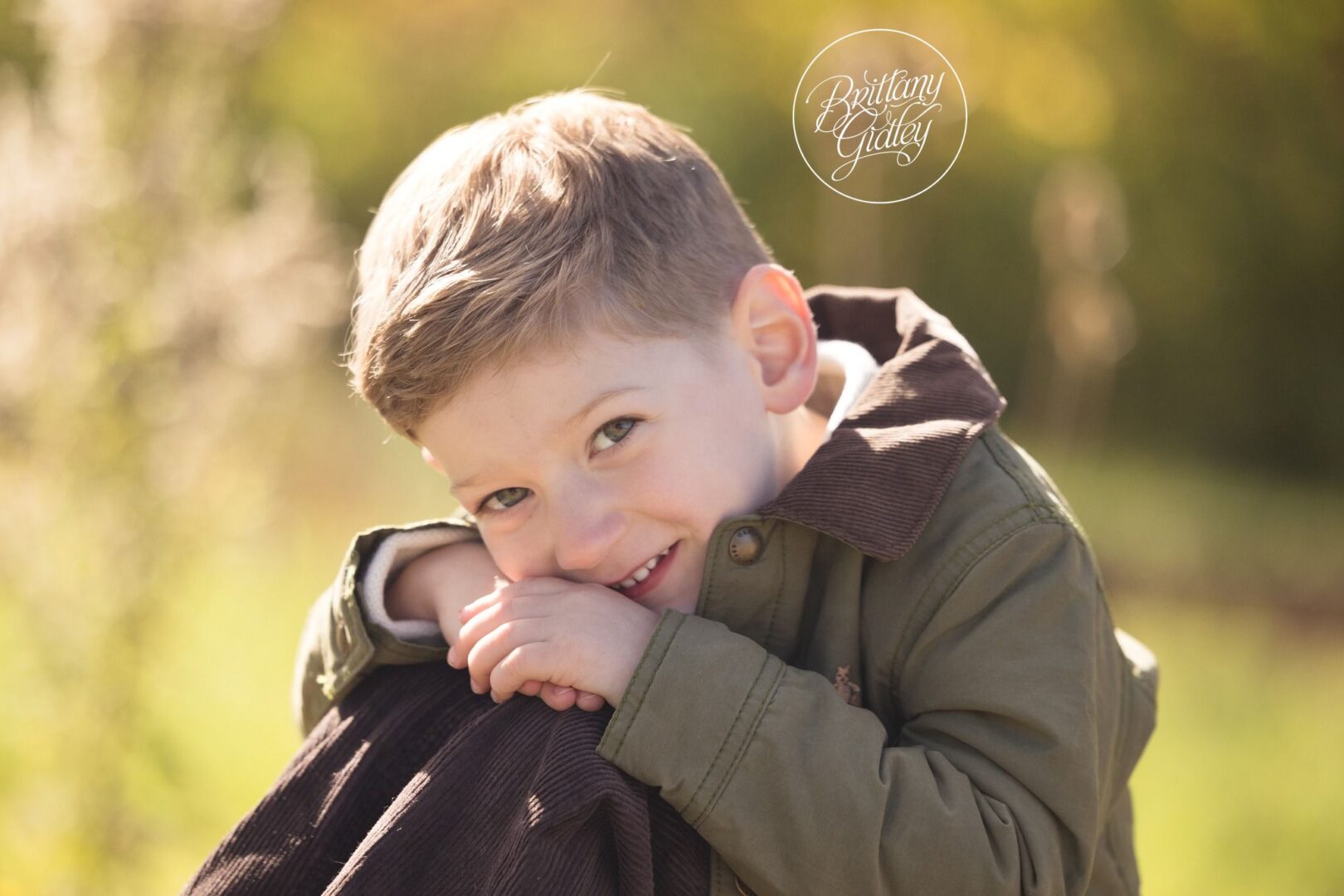 Smiling little boy hugging his knees in golden fall light in Brecksville, Ohio