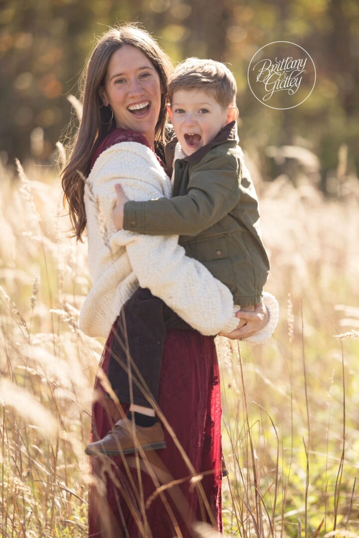 Mom holding her laughing son in the tall golden grass at Brecksville Reservation