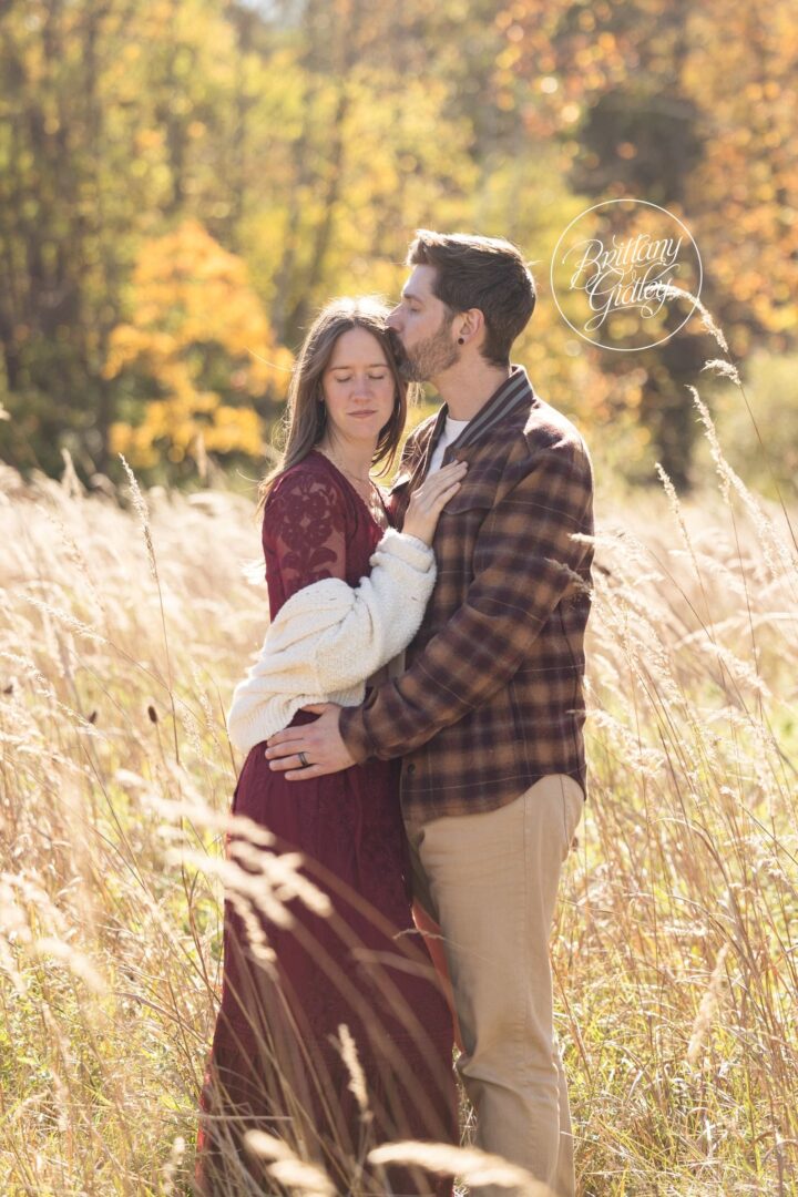 Dad kissing Mom's forehead in a fall meadow at Brecksville Reservation