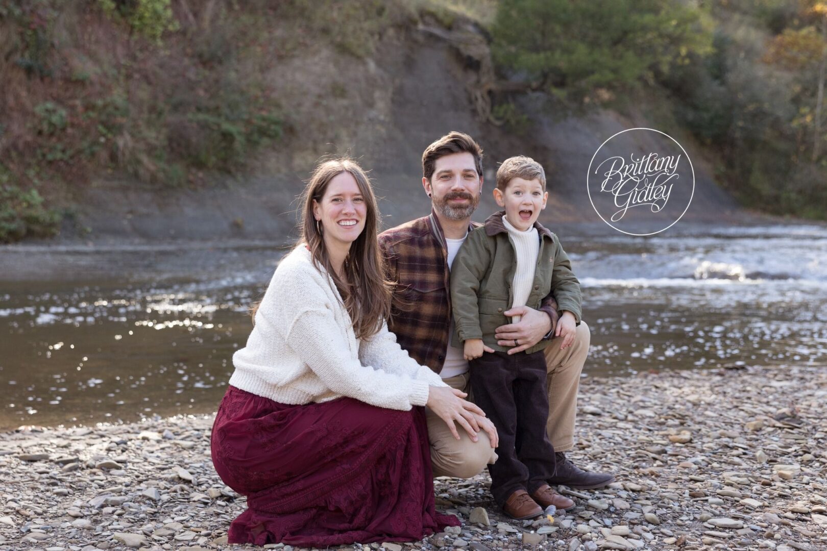 Mom, Dad and their son snuggled together by the river at Brecksville Reservation
