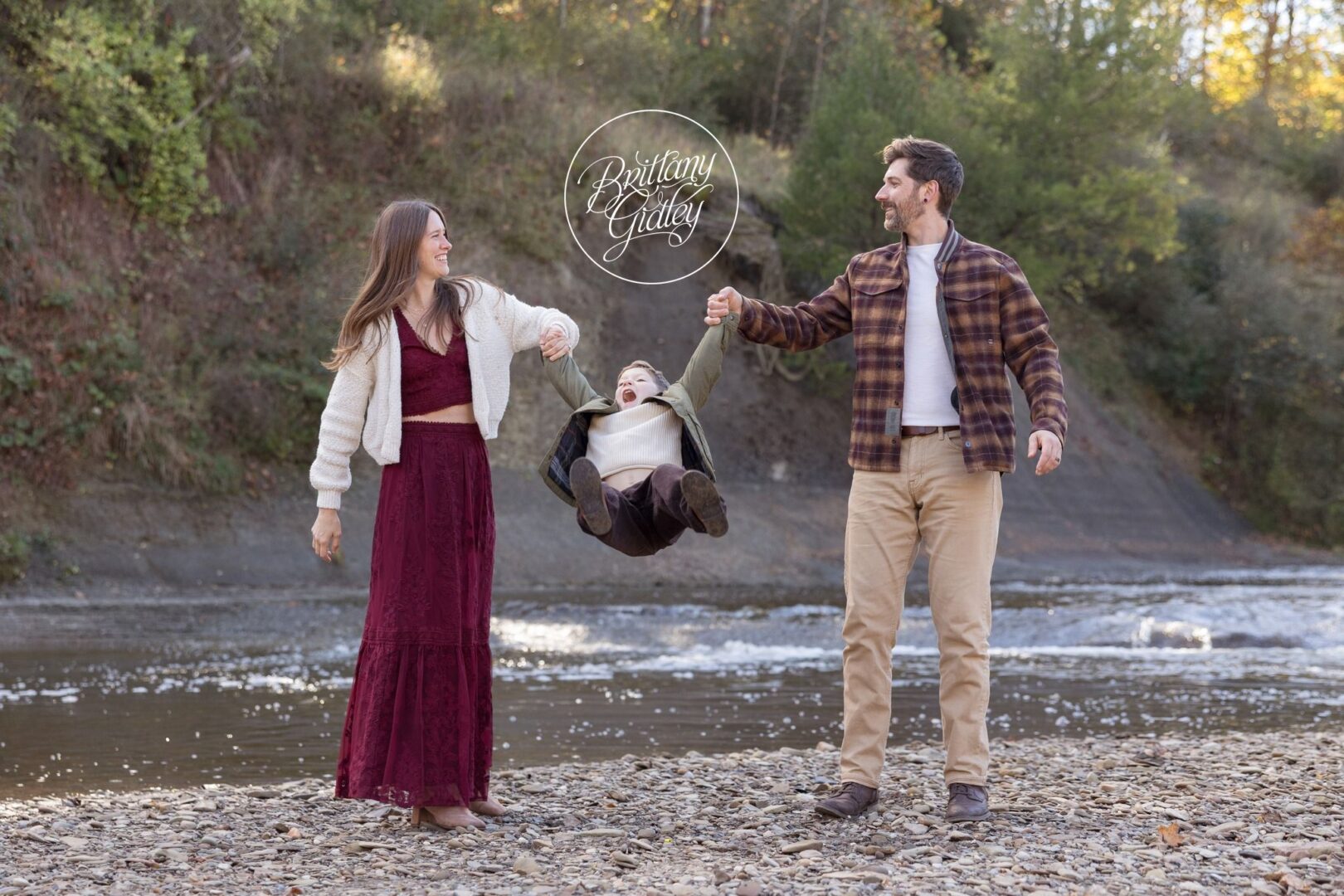 Mom and Dad swinging their son between them by the river in Brecksville, Ohio