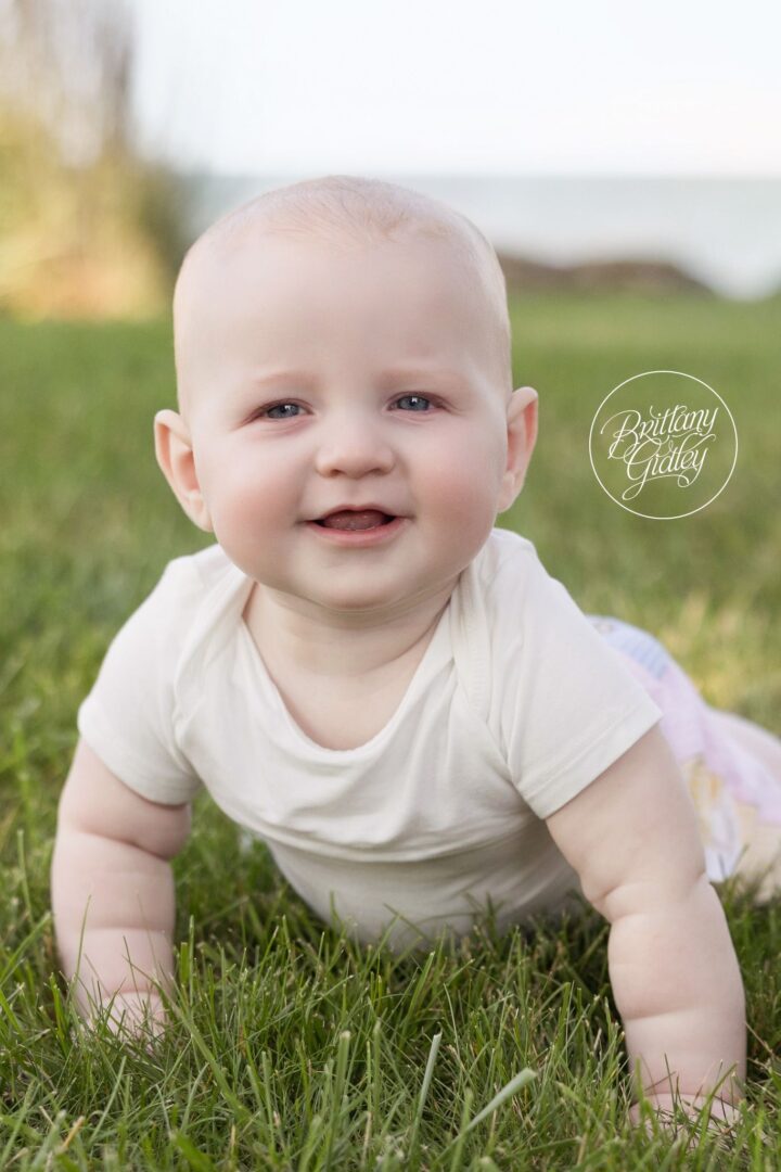Nolan smiling and crawling in the grass at his 6 month session