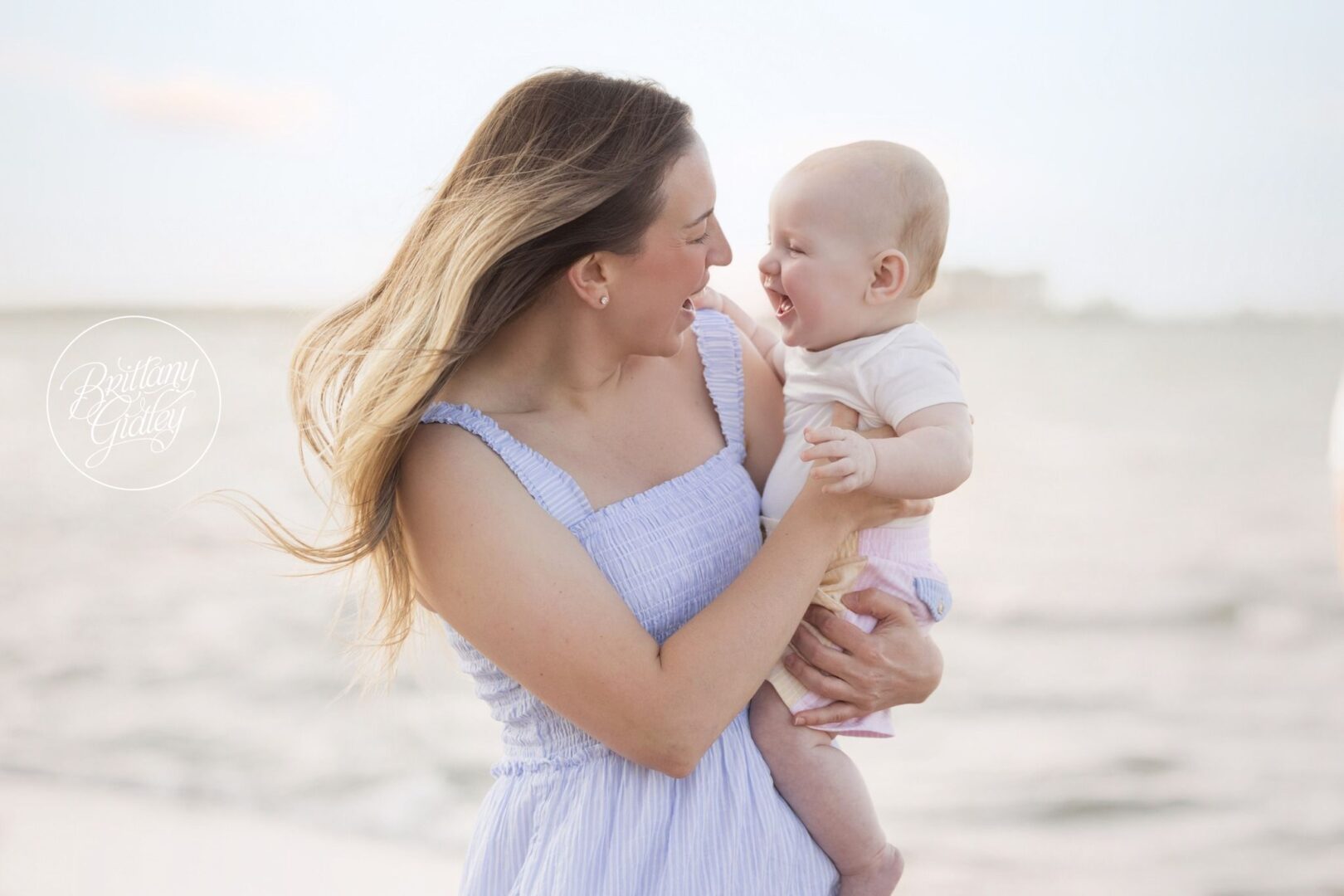 Mom laughing with Nolan on the beach at his 6 month photos