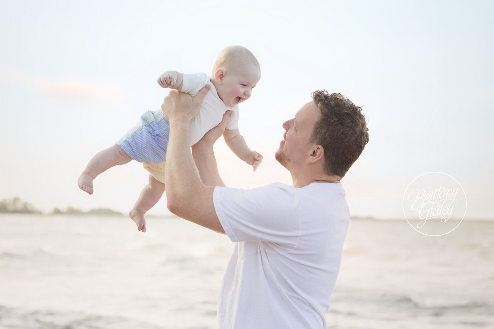 Dad lifting 6 month old Nolan into the air by the lake
