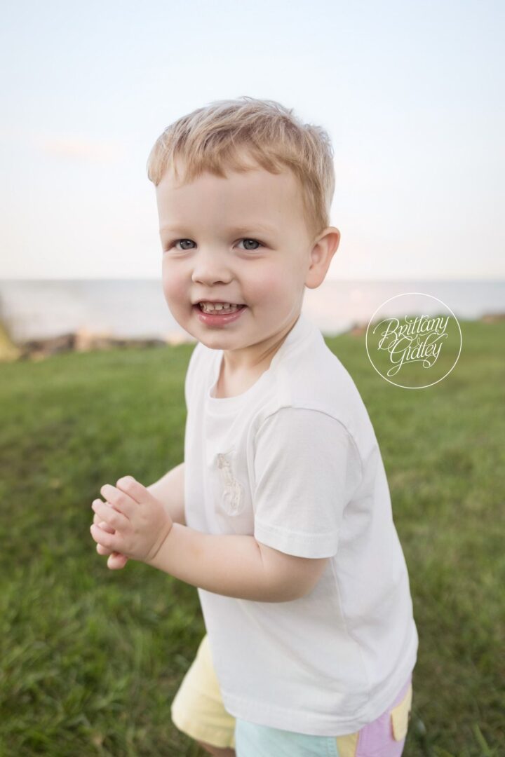 Big brother Miles grinning in the grass by the lake