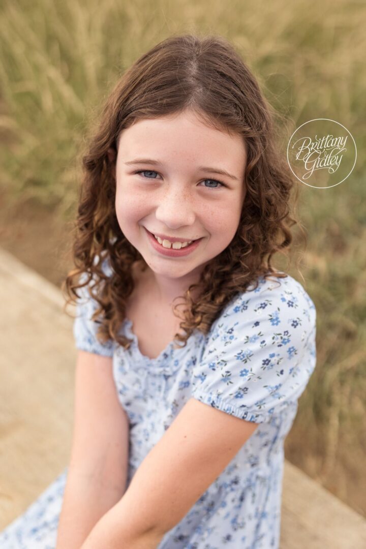 Curly-haired girl in a floral dress smiling at Edgewater Beach