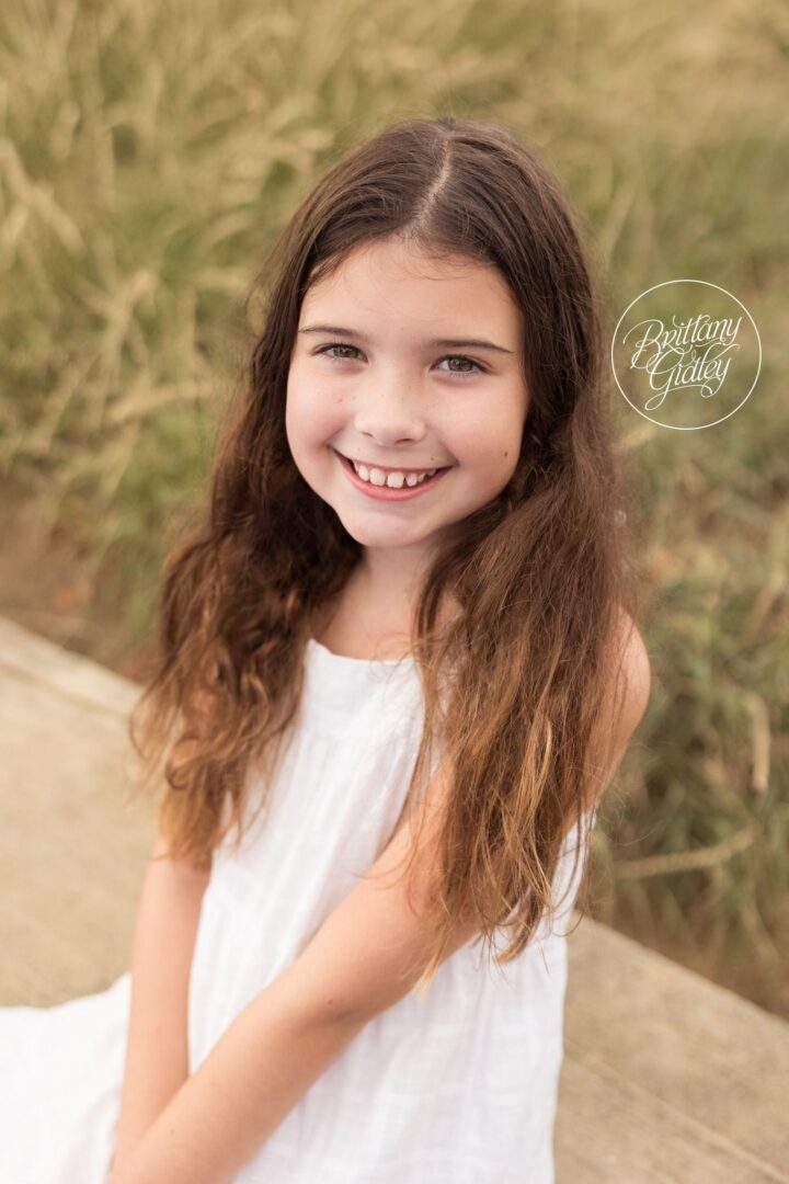Girl in a white dress with long hair in the beach grass