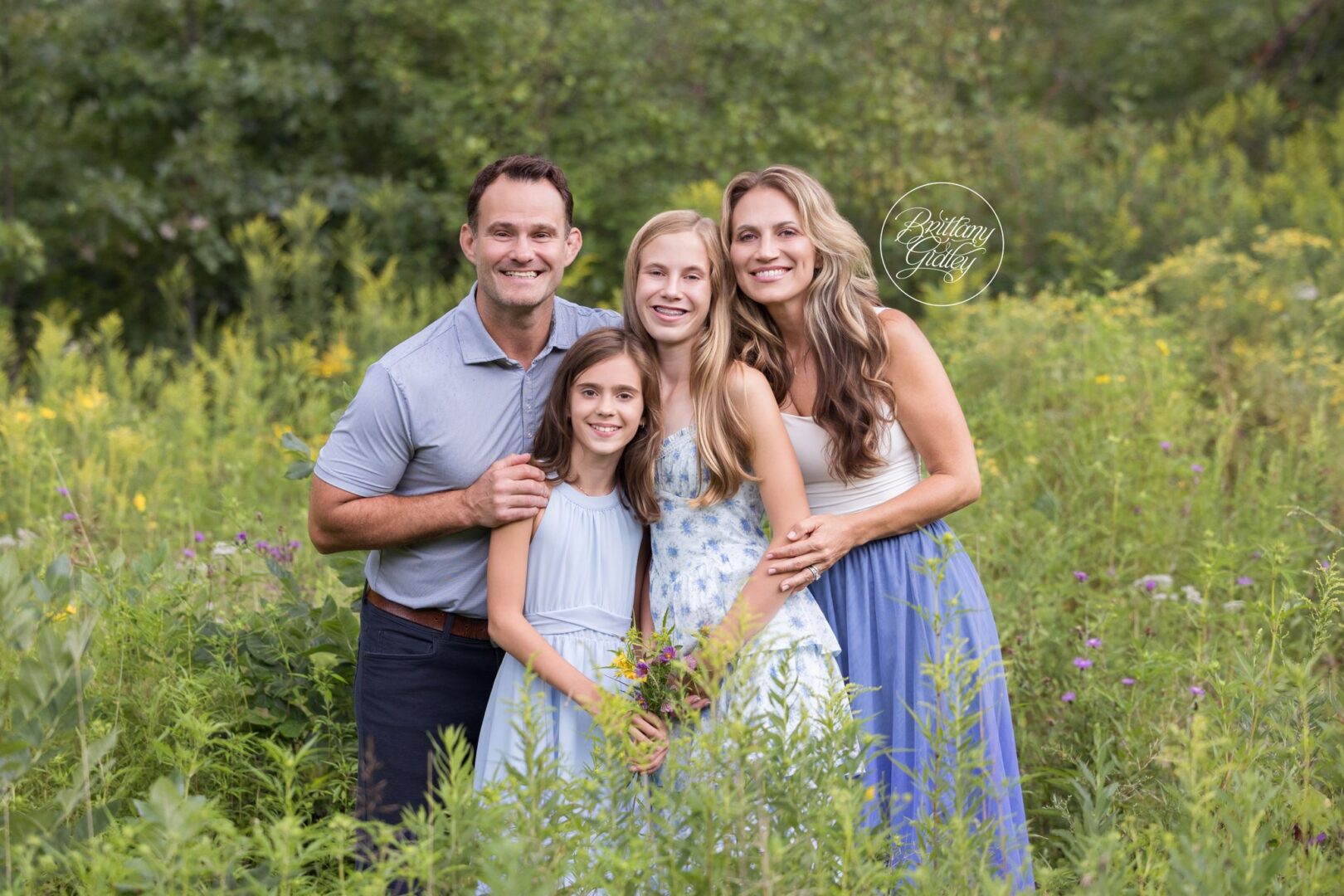 Waller family of four smiling together in a summer wildflower field at Bay Field in Bay Village, Ohio