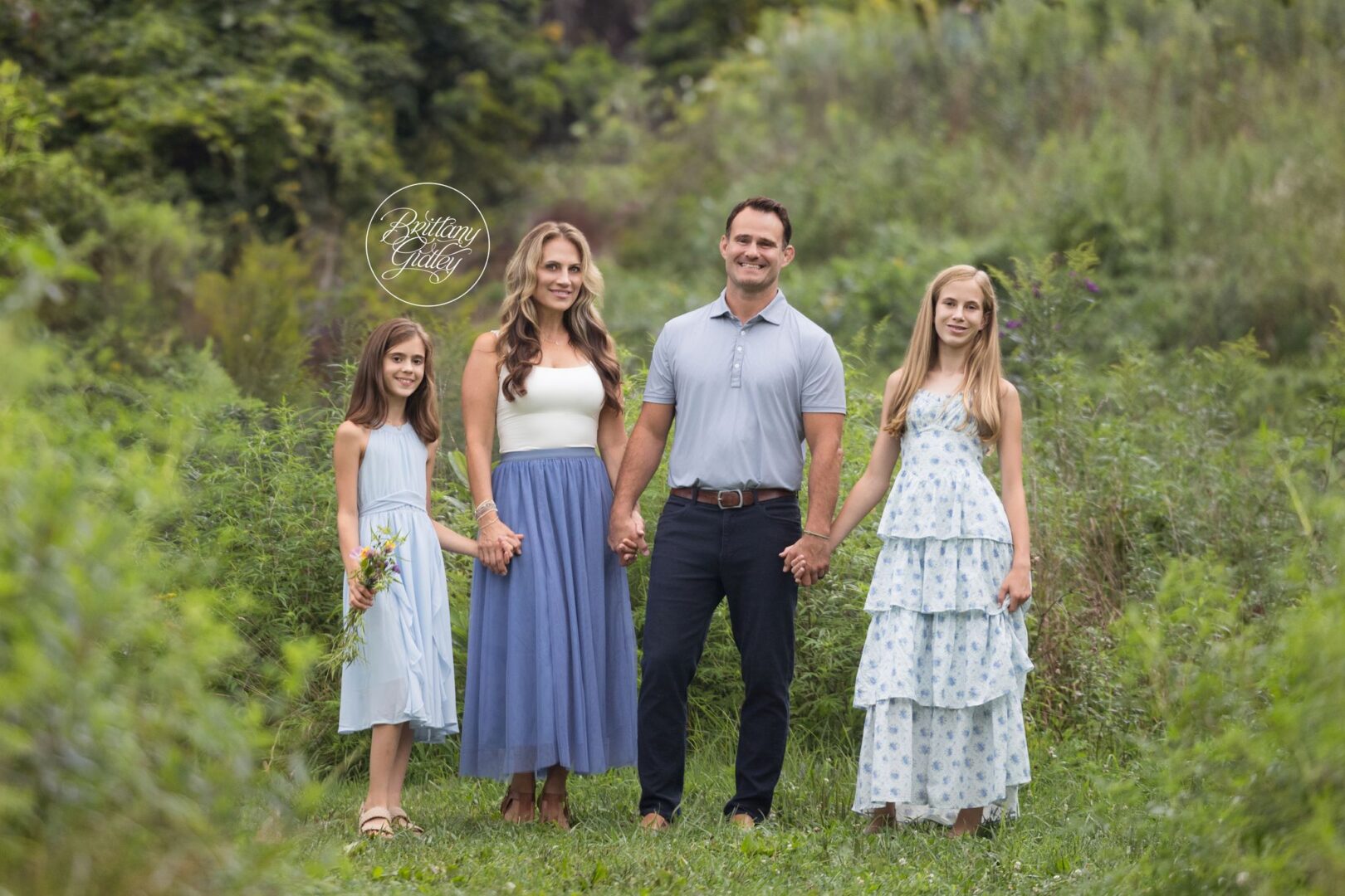 Mom, Dad and their two daughters holding hands in a green meadow, Cleveland family photographer