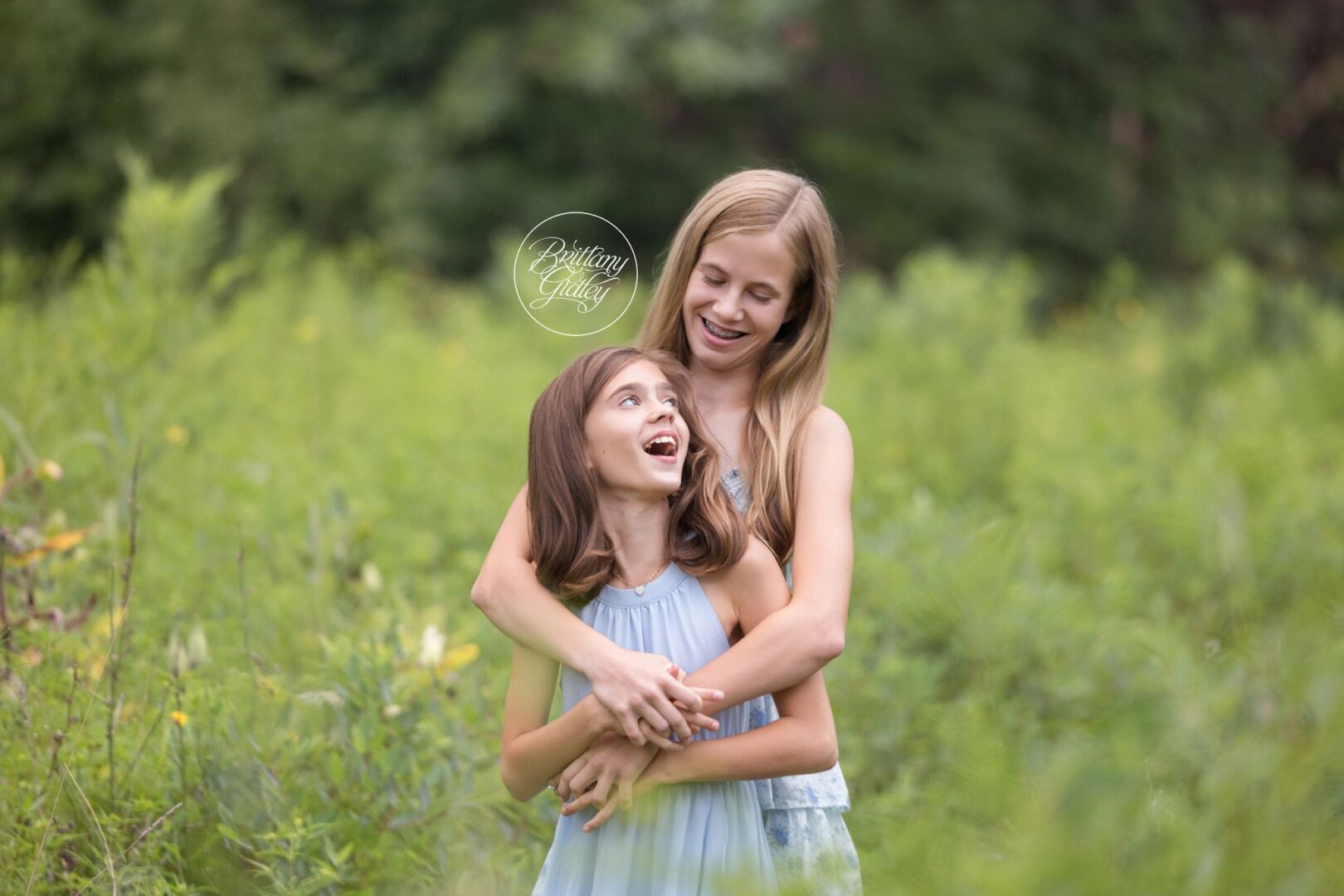 Big sister hugging her little sister in a wildflower field in Bay Village