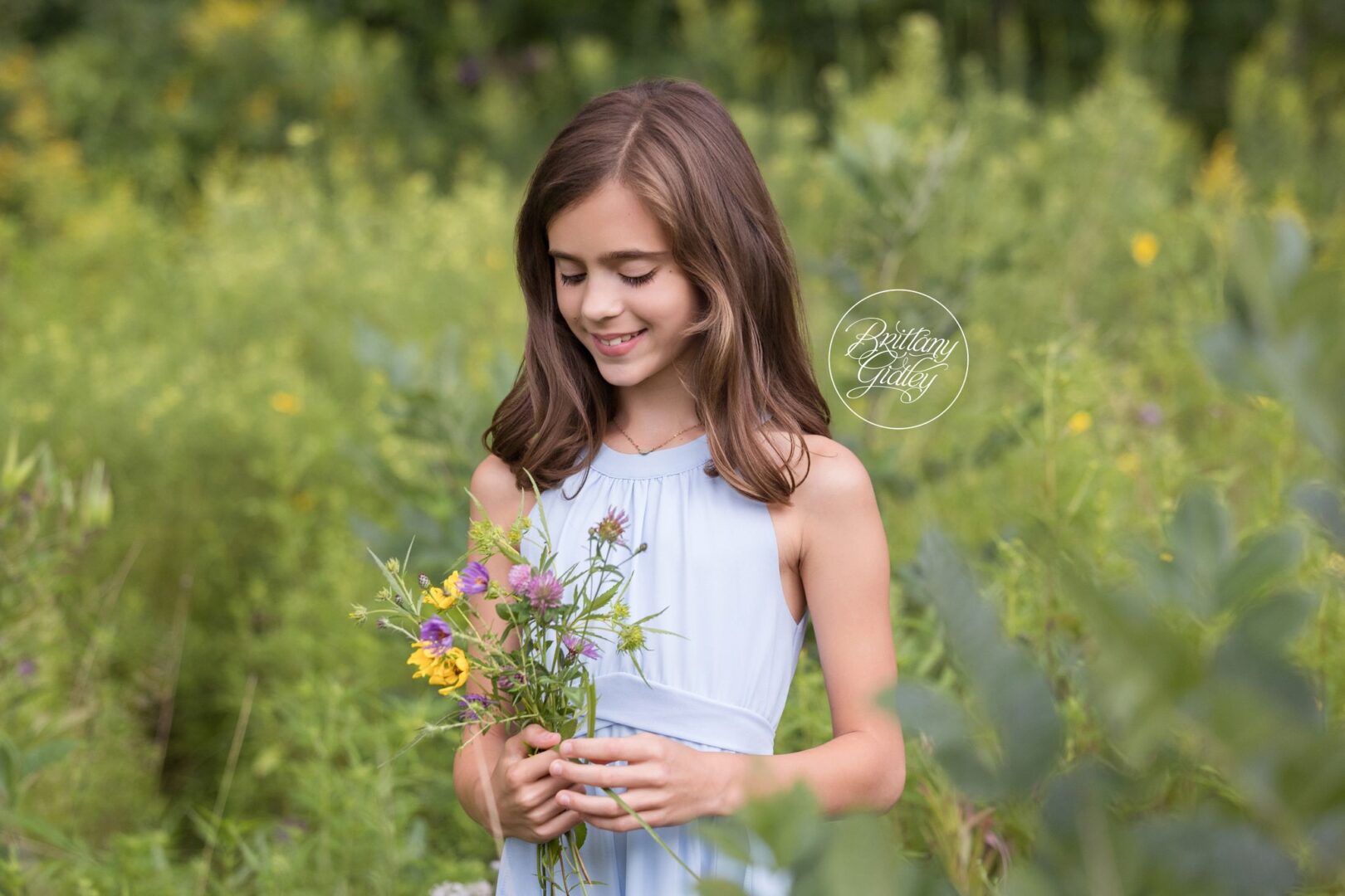 Girl in a light blue dress holding a handpicked wildflower bouquet
