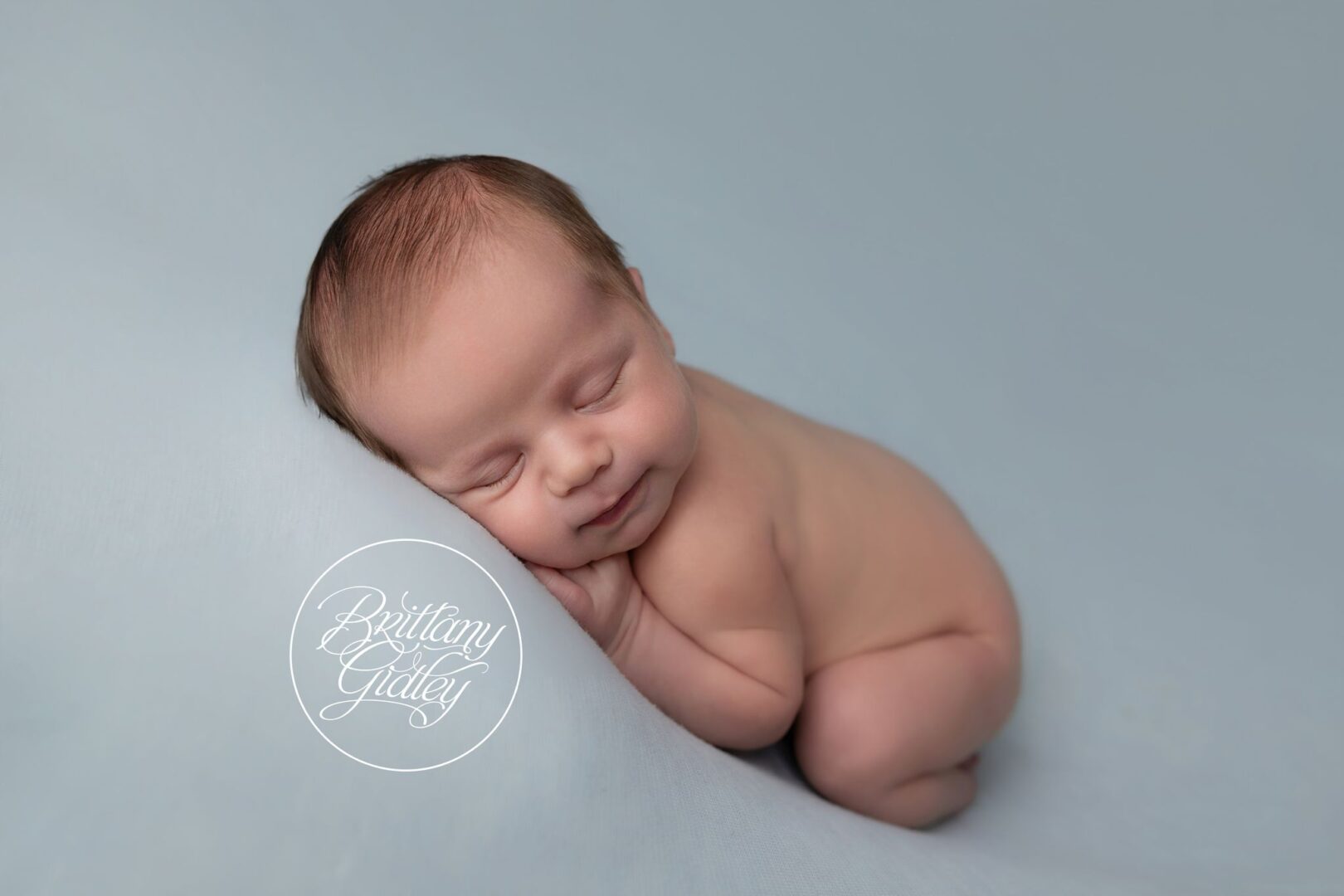 Newborn baby boy sleeping on his tummy on a soft blue backdrop, Erie PA newborn photography