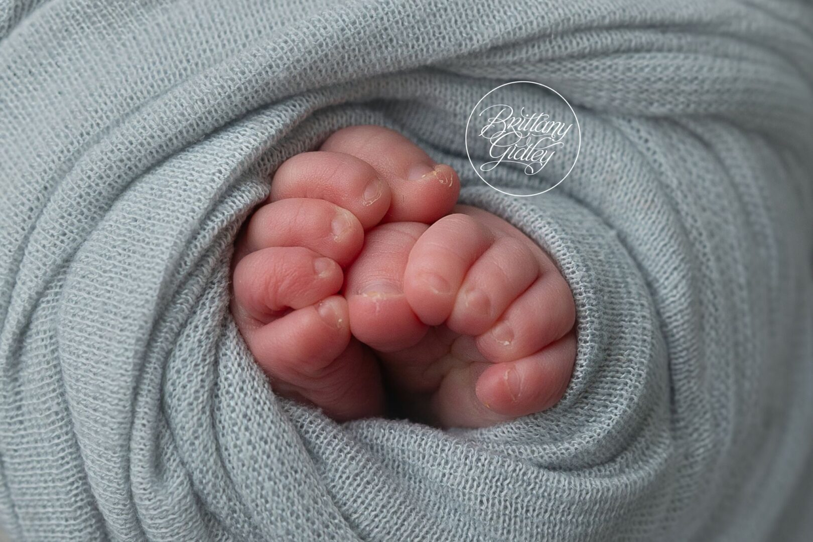 Tiny newborn toes peeking out of a blue knit wrap