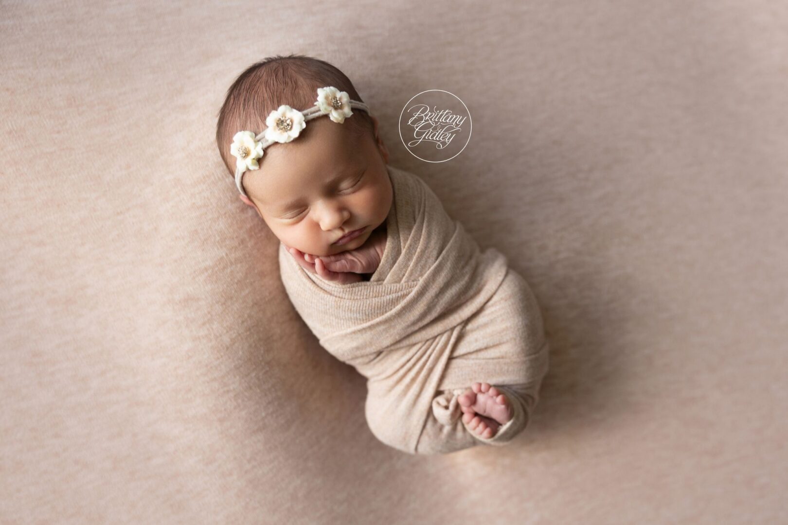 Newborn Isabel sleeping swaddled in blush with a flower crown in Coral Gables