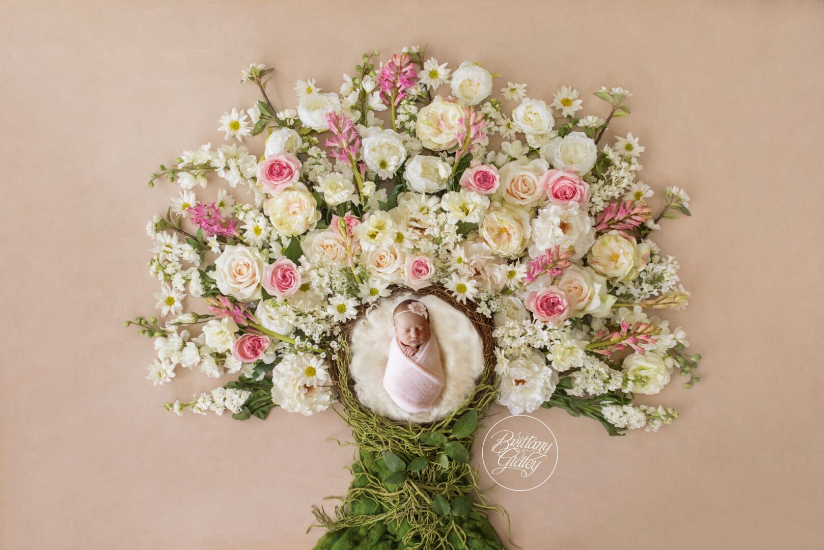 Newborn Isabel nestled in the center of a blooming tree of roses and wildflowers