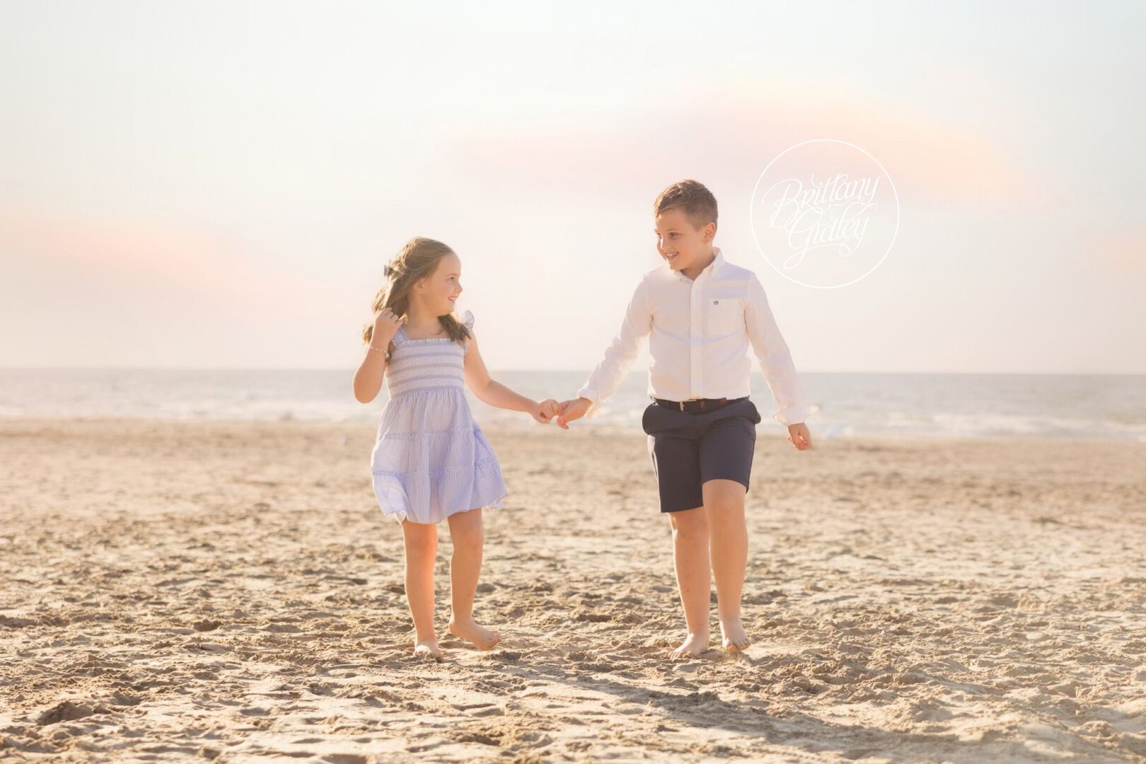 Brother and sister walking hand in hand on the sand at Edgewater Beach