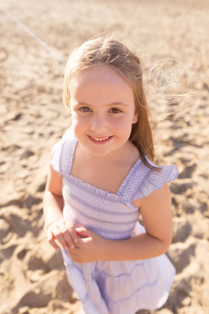 Smiling girl in a blue gingham dress on the sand at Edgewater Beach