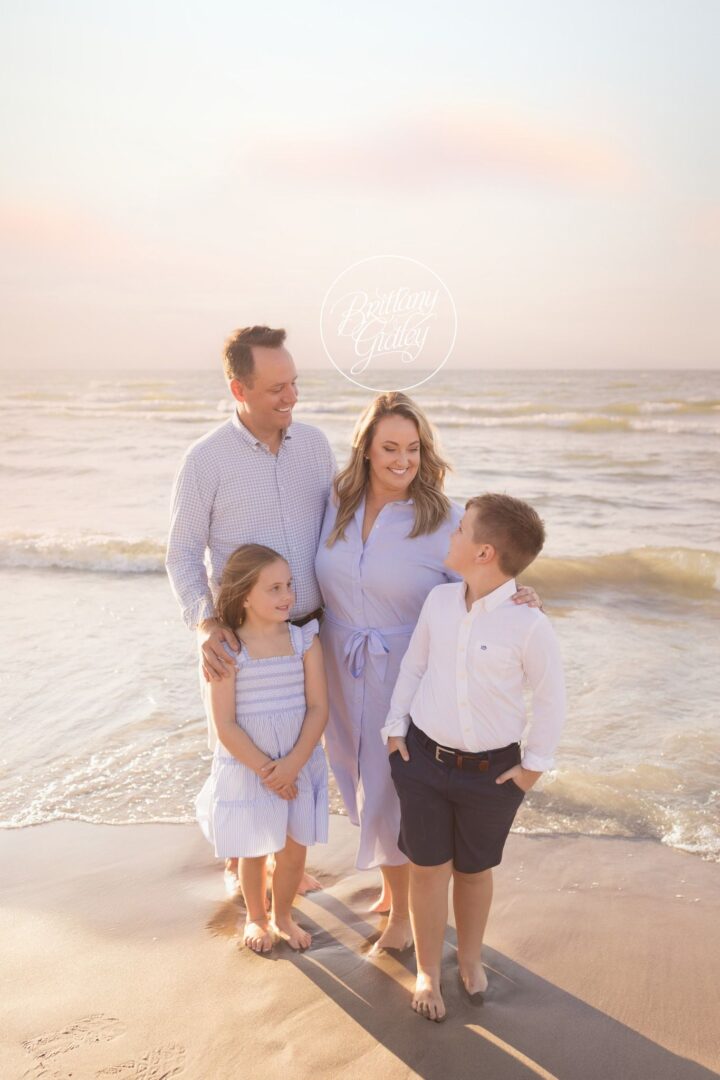 Family of four standing in the Lake Erie waves at sunset, Edgewater Beach family photos