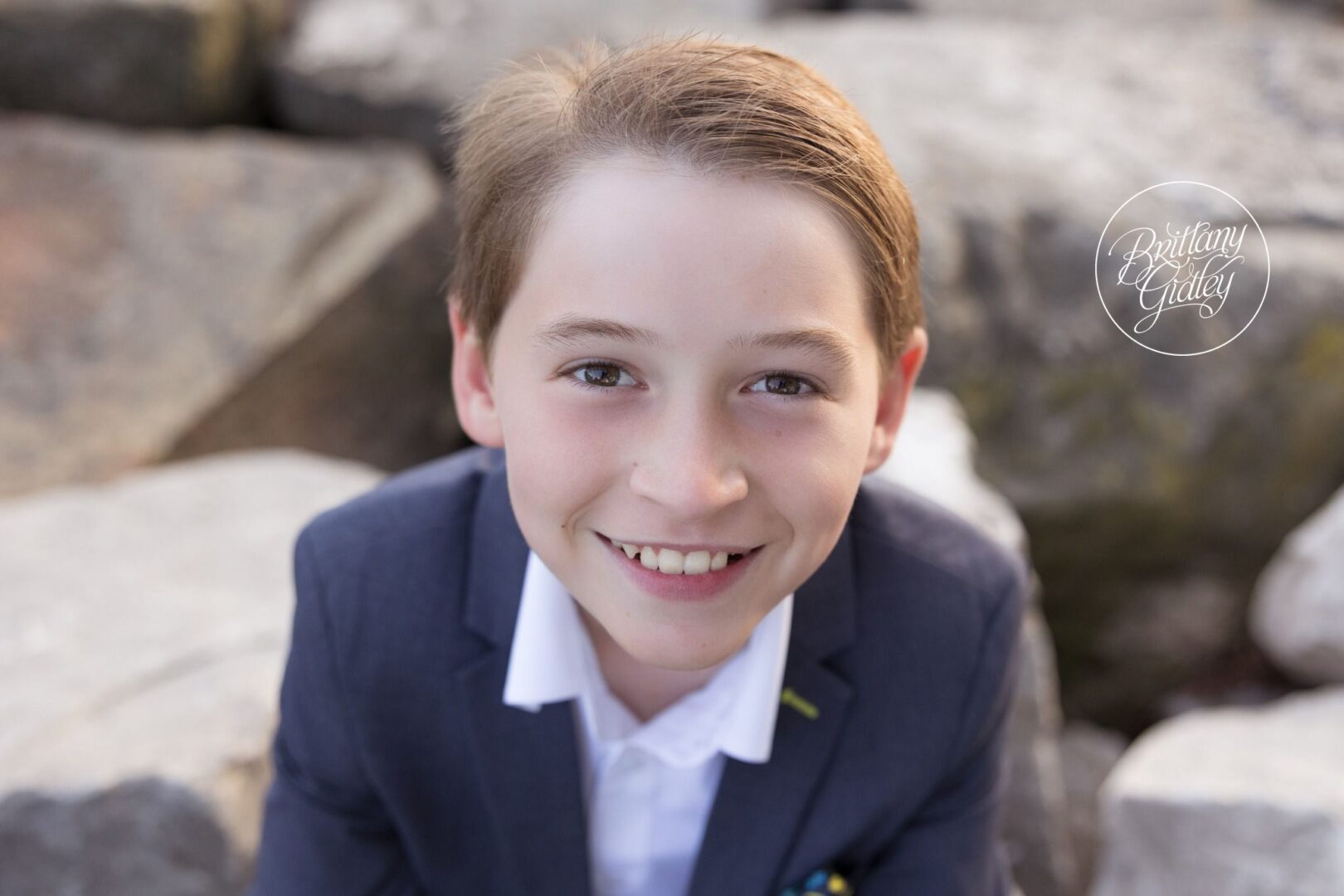 Smiling boy in a navy blazer on the rocks at Edgewater Beach