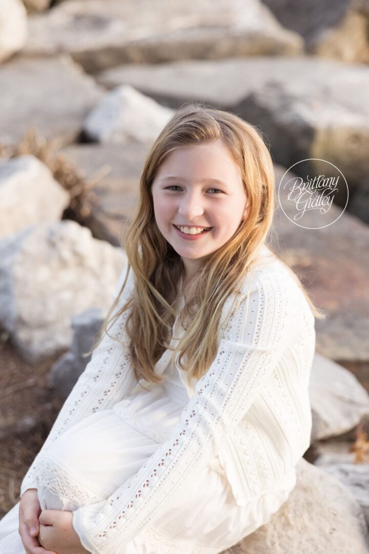 Girl in a white lace dress sitting on the rocks by Lake Erie
