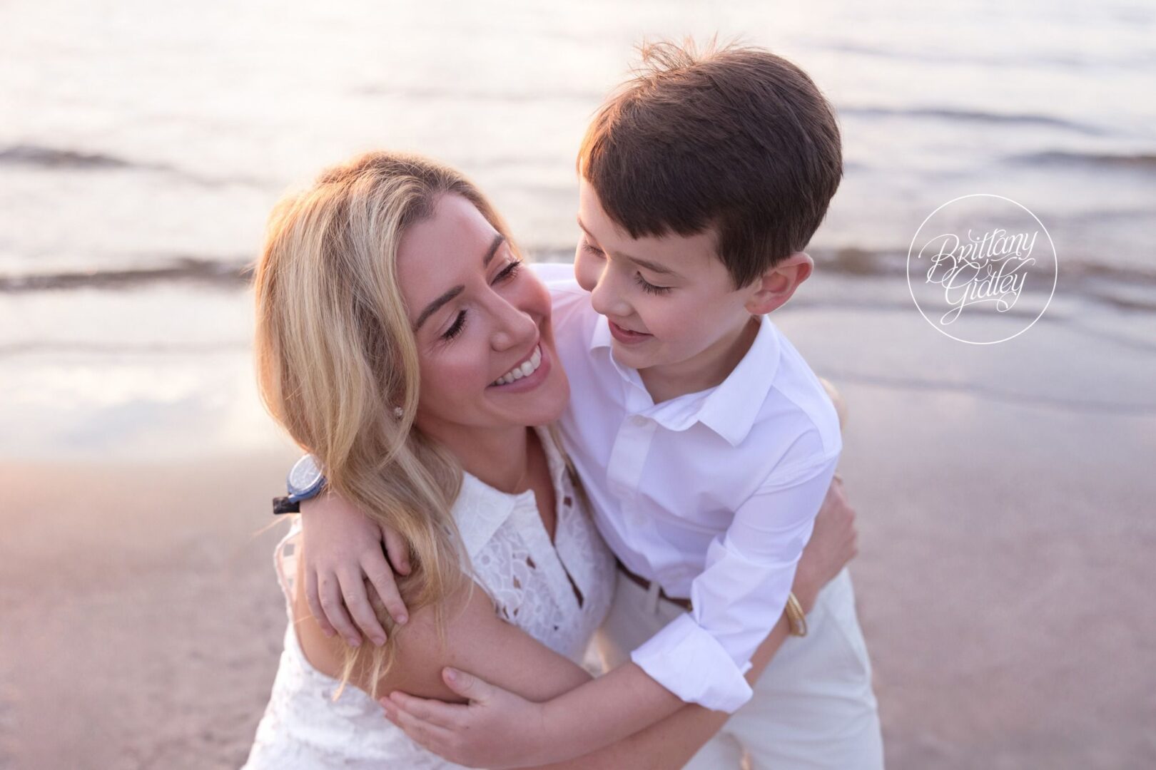 Mom and son snuggling on the beach at Edgewater Park