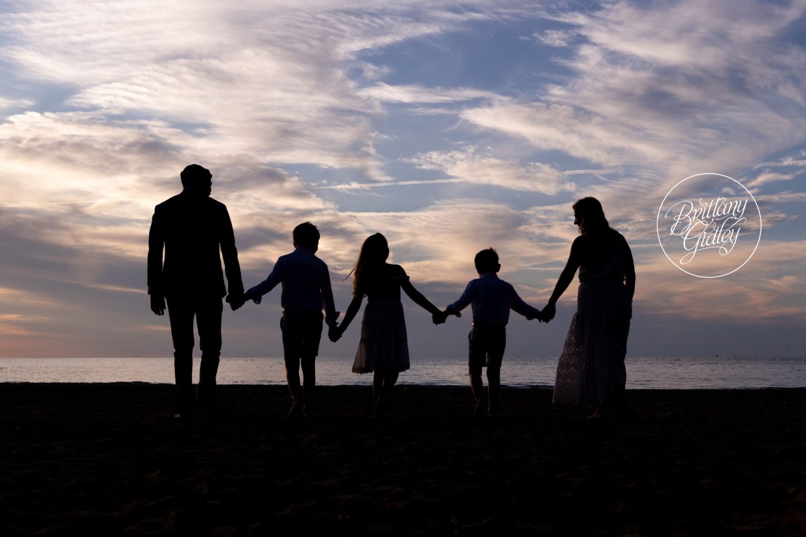 Mitchell family silhouette holding hands at sunset on Lake Erie