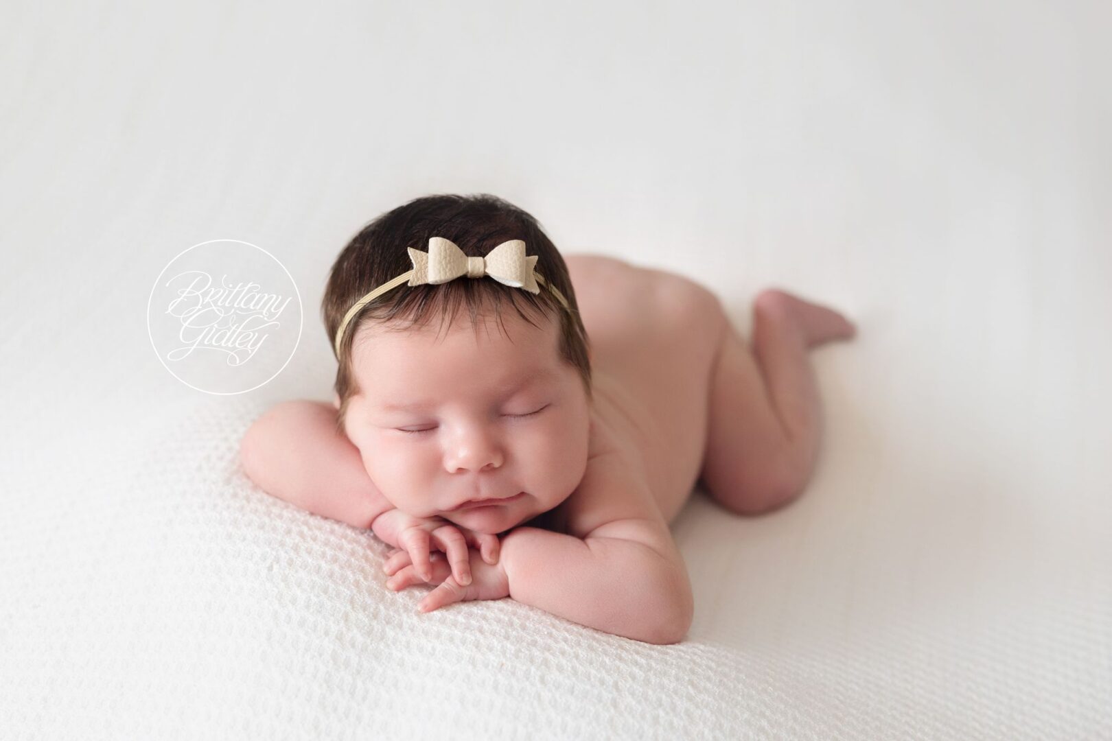 Newborn baby girl with dark hair resting her chin on her hands, Naples Florida newborn photography