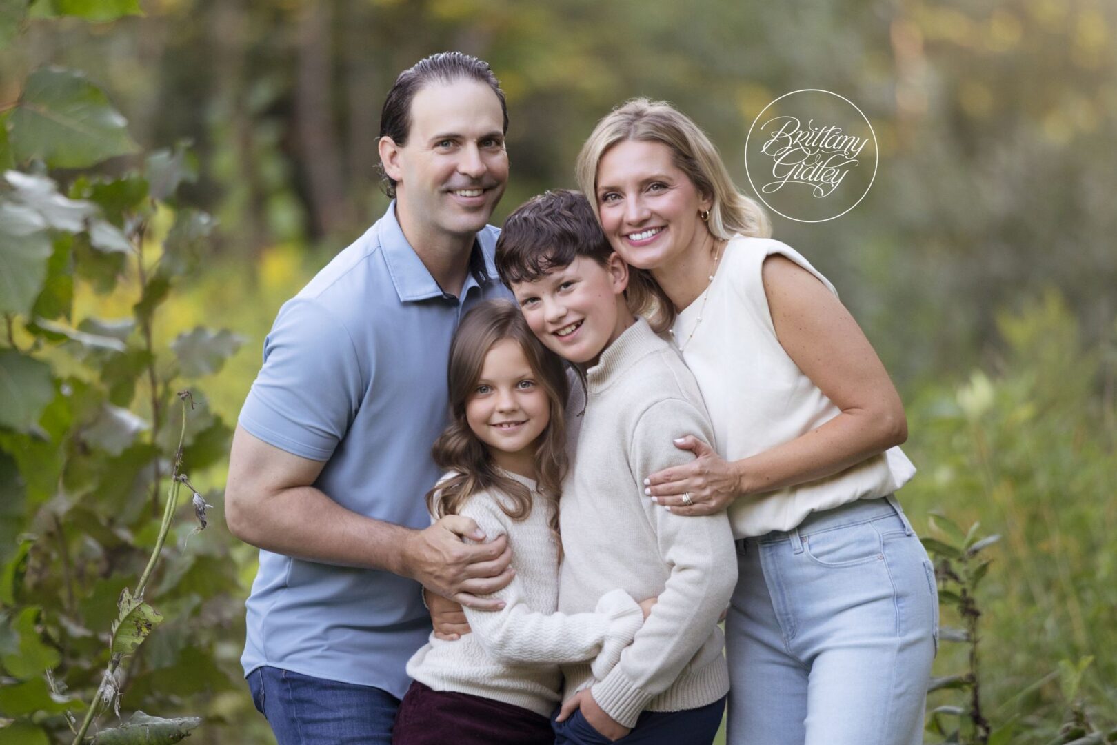 Mom, Dad, son and daughter in a big snuggly family hug among the greenery at Bay Field