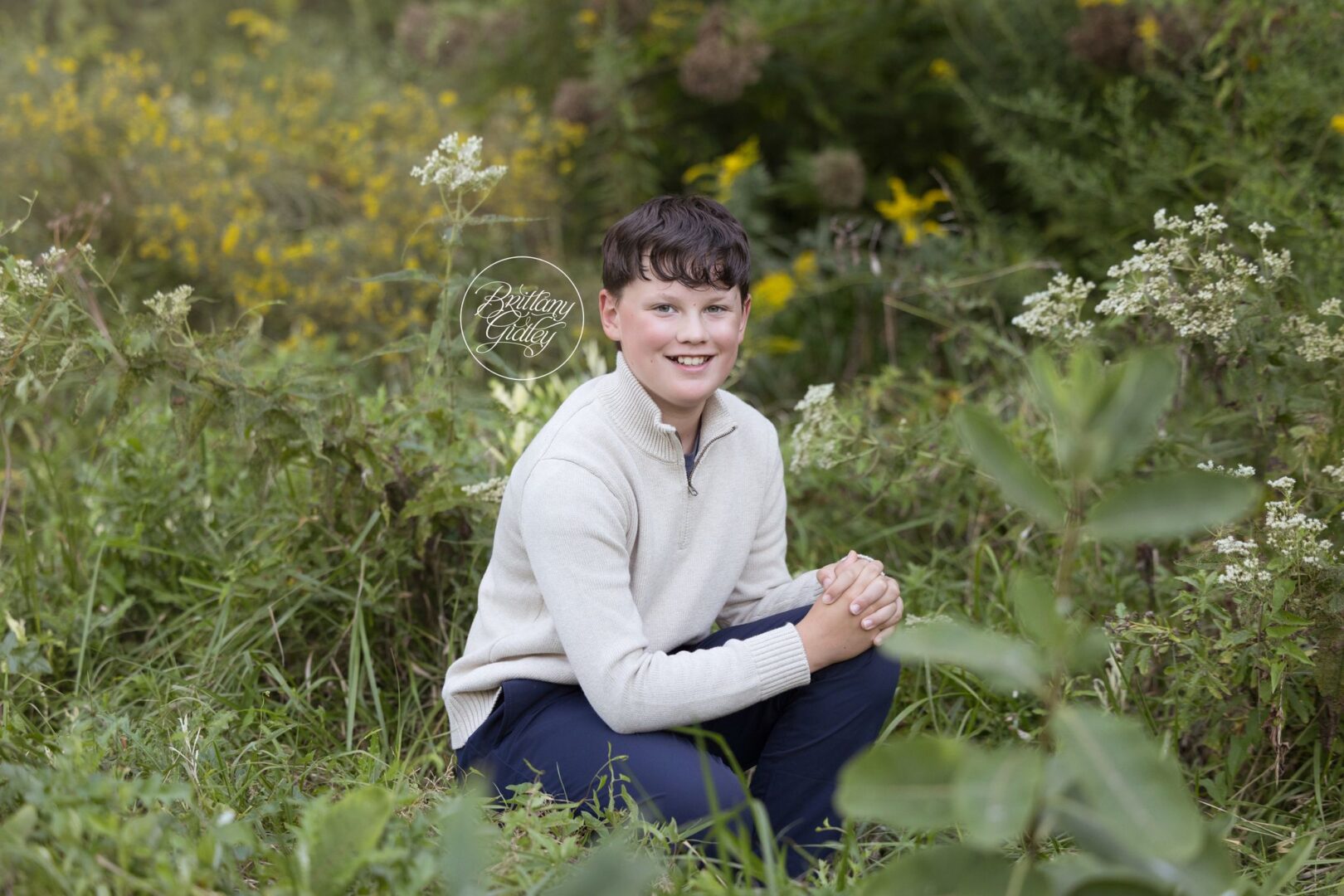 Boy in a cream quarter-zip sweater kneeling among wildflowers in Bay Village, Ohio