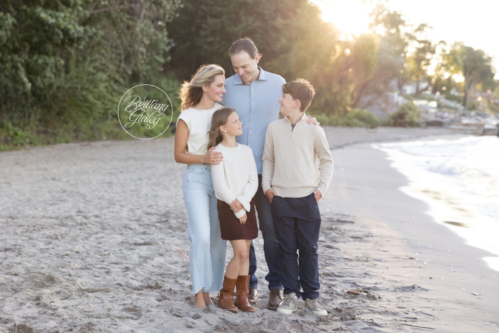Family of four standing together on Huntington Beach with Lake Erie and the setting sun